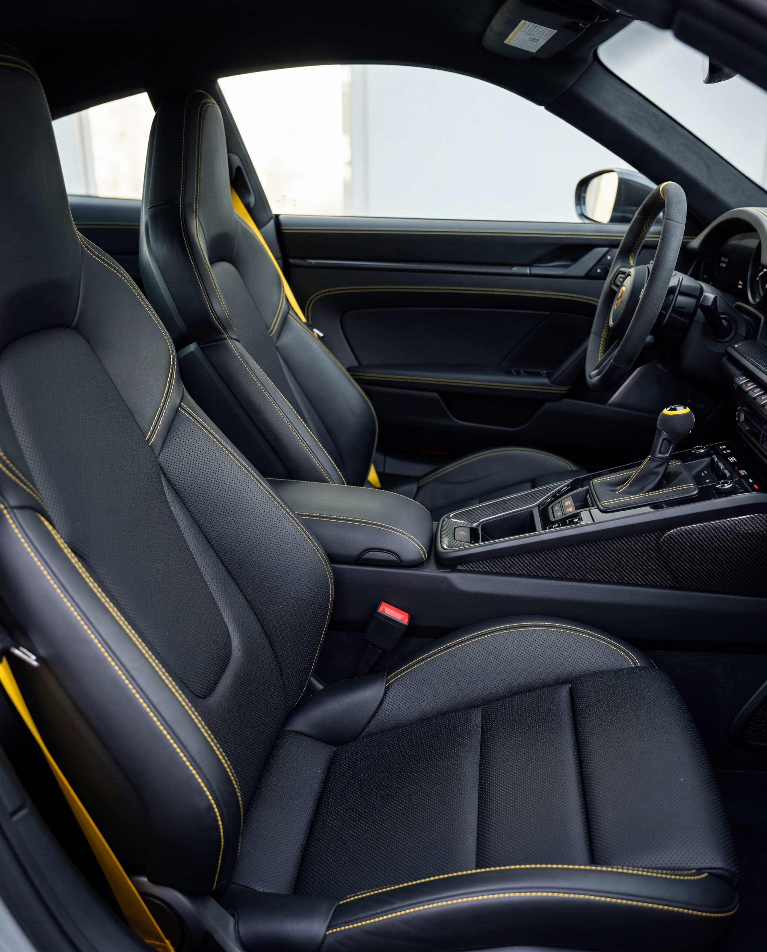 Interior de un auto con asientos de piel negra y costuras amarillas, limpio y acondicionado